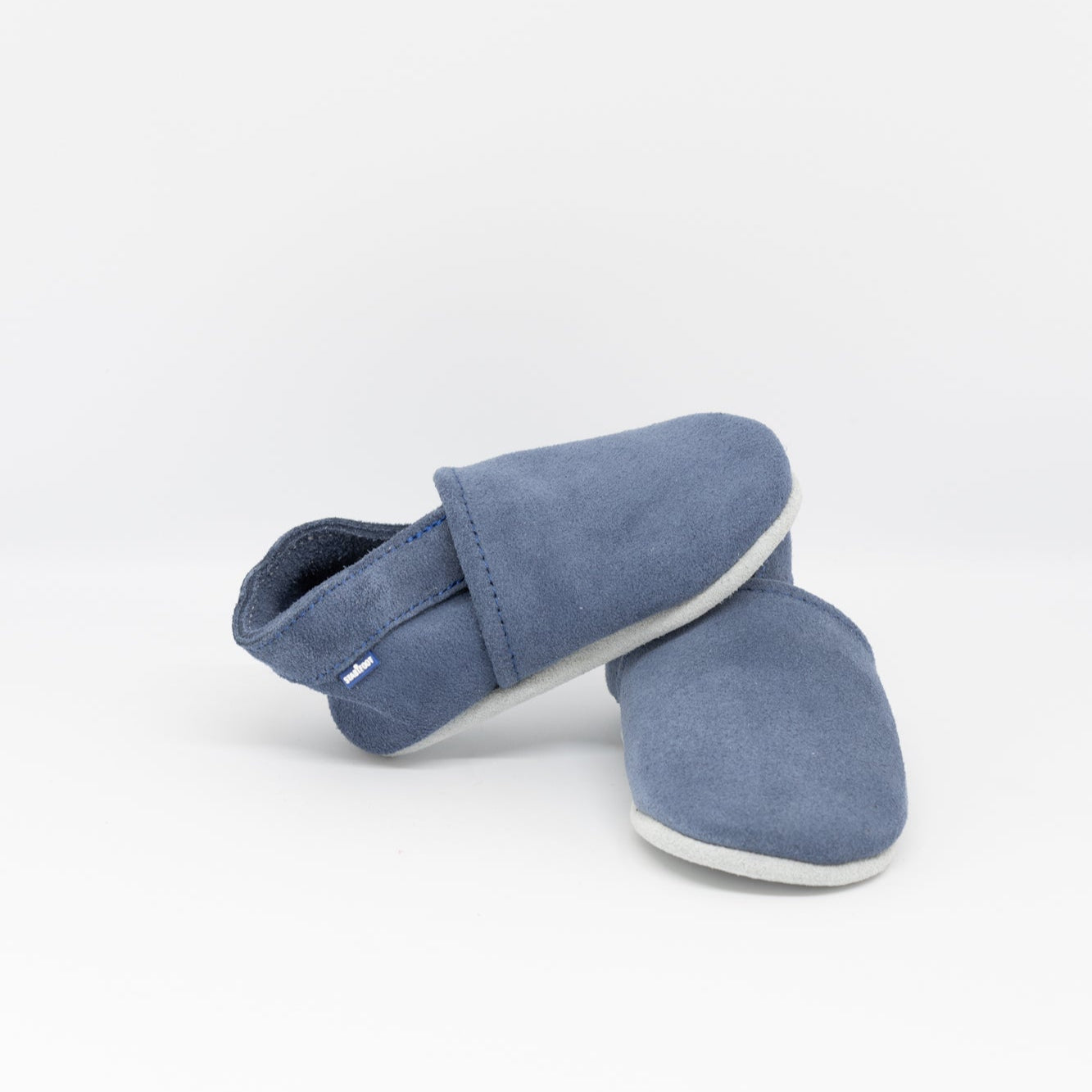 Our leather babysoft slippers are designed for a secure and comfortable fit. The hidden elastic at the heel keeps them snugly in place — no more lost babyshoes! The seams are stitched on the outside for extra comfort, and the soft leather naturally regulates temperature, keeping little feet cozy year-round. Delivered in a charming cotton bag, they’re a stylish and practical gift.
The next best thing to bare feet.
0-3 months (10 cm), 3-6 months (11 cm), 6-12 months (12 cm), 12-18 months (13 cm